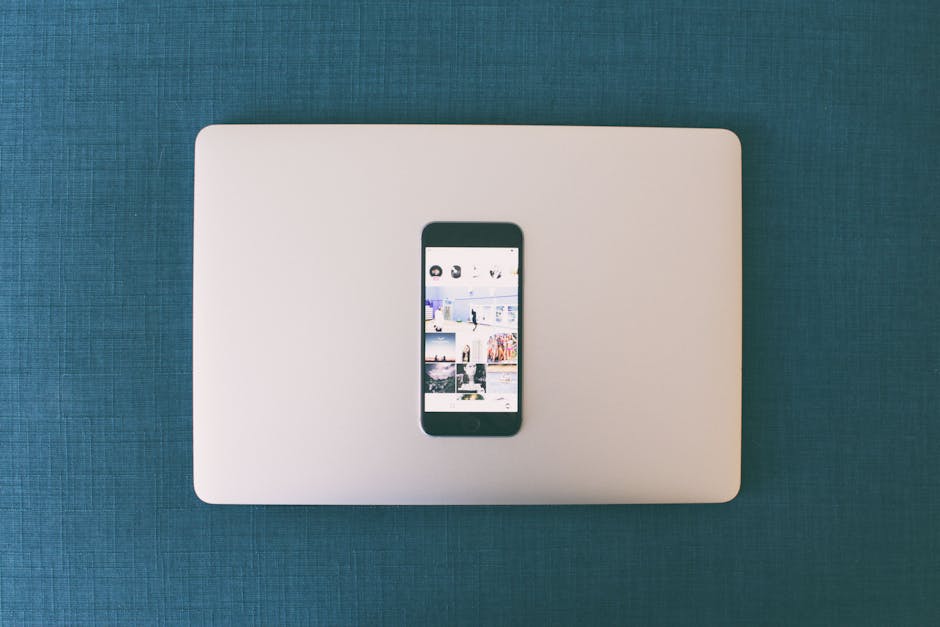 Flat lay of a smartphone on a laptop with social media photos on screen